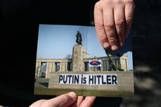 An Austrian activist at the Ukrainian stall shows a photo of himself taken at the Soviet memorial in Tiergarten park when Russia invaded Ukraine.