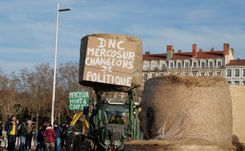 The farmers on the pont Wilson in Lyon with a protest sign reading "DNC [lumpy skin disease], Mercosur, let's change policy".