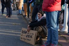 A farmer sitting down during the demonstration with a sign reading: "Farmer - as a kid you dream of it, as an adult you die from it."